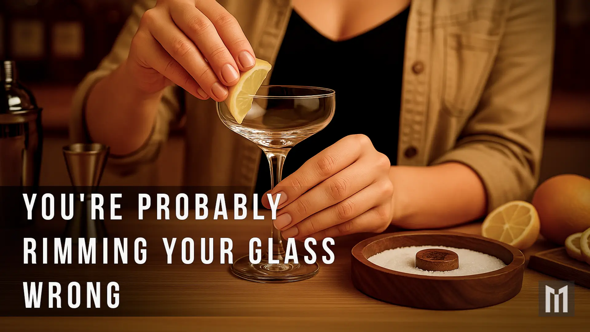 Home bartender using a lime wedge to moisten the rim of a cocktail glass beside a wooden bar rimmer filled with salt.