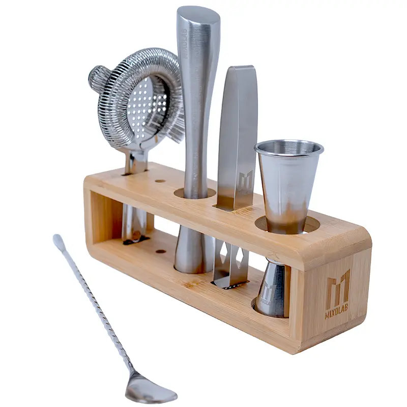 Cocktail kit with stainless steel cocktail accessories in a bamboo stand, including jigger, muddler, ice tong, strainer, and bar spoon.