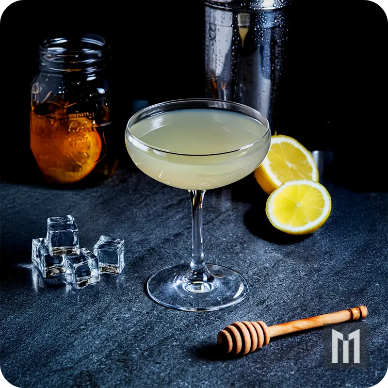 Classic Daiquiri in a coupe glass with lime, rum, and syrup, served on dark surface with shaker and lime garnish.